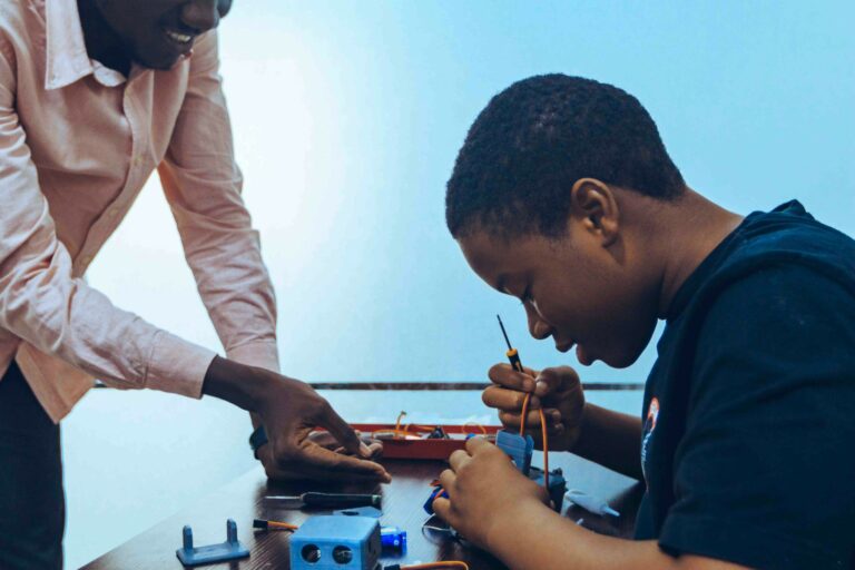 A student and a teacher engage in practical electronics learning in a classroom environment.