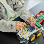 Young student assembling a toy car with electronic components, focusing on STEM education.